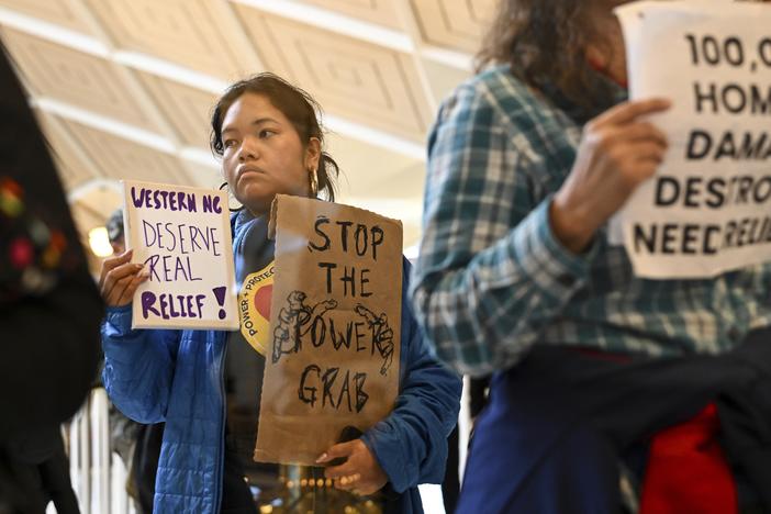 A protester holds a sign as the Republican-dominated North Carolina House convened to complete the override of Gov. Cooper's veto, Dec. 11, 2024, in Raleigh, N.C.