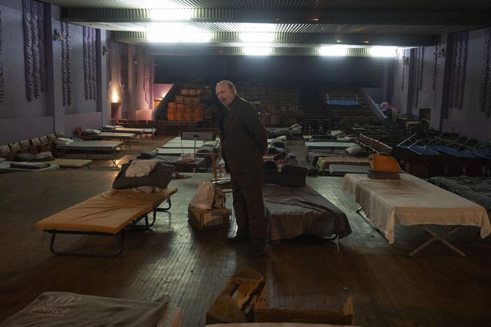 A man waits for evacuation to western Ukraine as he stands by a bed in a city theatre that hosts refugees running from Russian offensive in the Donetsk region, in Pavlohrad, Dnipropetrovsk region, Ukraine, Thursday, Dec. 12, 2024.