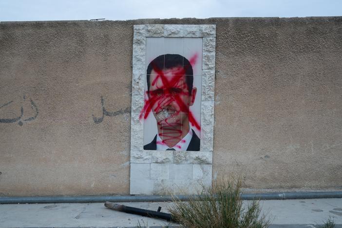 A poster of Bashar al-Assad is defaced with red paint on a wall in Damascus, Syria, on Dec. 11.