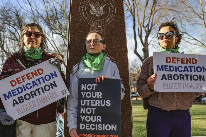 Three members of the Women's March group protest in support of access to abortion medication outside the Federal Courthouse on March 15, 2023, in Amarillo, Texas.