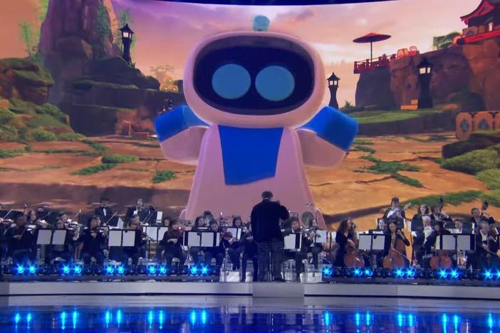 The titular Astro Bot looms over an orchestra playing a medley from the soundtracks to the six Game of the Year nominees.