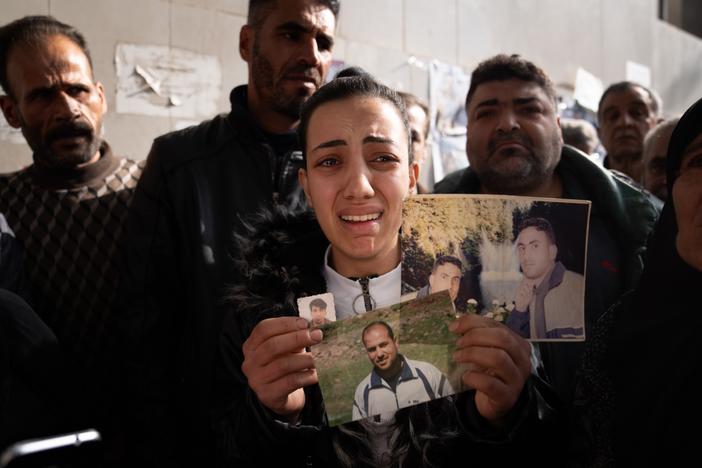 Sarah Abdel Hamid Al-A'ami holds photos of her 4 brothers who were all accused of terrorism under the Assad regime, and though she came to search posters of dead bodies, she still hasn't found any signs of them.