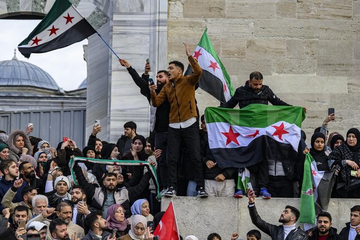 Syrian residents in Turkey wave Syrian opposition flags as they celebrate the President Bashar al-Assad's rule in Syria after rebel fighters took control of Damascus overnight, at the Fatih Mosque, in Istanbul, on December 8, 2024.