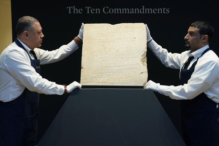 Sotheby's workers hold the stone tablet of the Ten Commandments that is scheduled for auction.