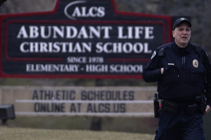 A police officer stands guard in front of Abundant Life Christian School on Monday in Madison, Wis.