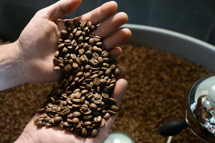 A roaster holds coffee beans ready to be ground. The cost of raw, or green, coffee has soared following a drought in top-grower Brazil.