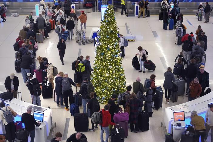 Holiday travelers wait in line to check their bags at the JetBlue terminal at Boston's Logan Airport on Friday.