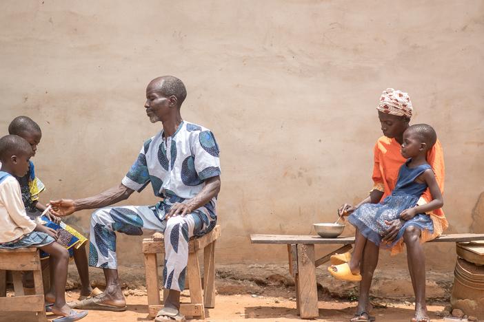 Toyin feeds her 3-year-old daughter, Kudirat, while her husband, Saheed, tends to their other two children.