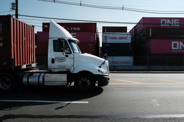 Trucks move past cargo containers at a port in Bayonne, N.J., in 2021. The state is adopting California's Advanced Clean Trucks rules, which require at least 7% of medium- and heavy-duty vehicles sold in the state to be zero-emission for model year 2025. Dealers are petitioning for a delay, so far unsuccessfully.
