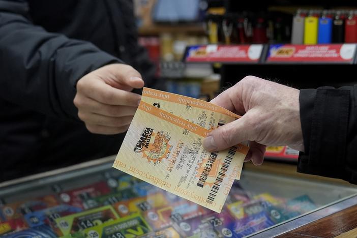 Rob, right, buys a Mega Millions ticket at Rossi's Deli in San Francisco, Thursday, Dec. 26, 2024.