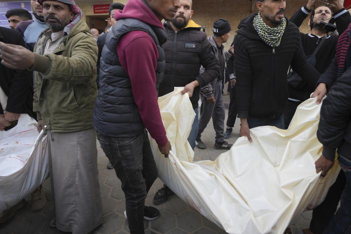 Palestinians carry white sacks containing the bodies of those killed in overnight Israeli airstrikes on the Maghazi refugee camp, at Al-Aqsa Hospital, in Deir al-Balah, central Gaza Strip, on Saturday.