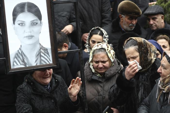 People mourn at the grave of flight attendant Hokume Aliyeva during a funeral of the crew members of the Azerbaijan Airlines Embraer 190 killed in a deadly plane crash in Kazakhstan this week, at the II Alley of Honor in Baku, Azerbaijan, Sunday, Dec. 29, 2024.