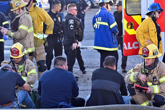 Firefighters tend to people after a plane crashed through the roof of a building near Fullerton airport on Jan. 2, 2025, in Fullerton, Calif.