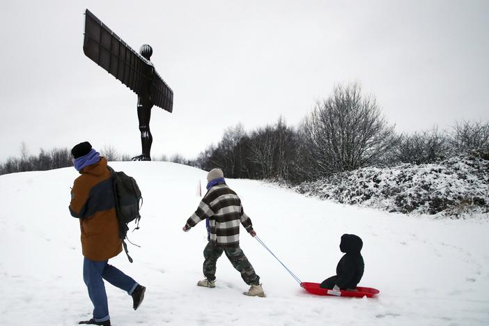A lady is seen pulling her child along on a sledge as they admire Anthony Gormley's sculpture, the Angel of the North, which is surrounded by heavy snow in Gateshead, North East England, as the severe weather continues across England, on Sunday.