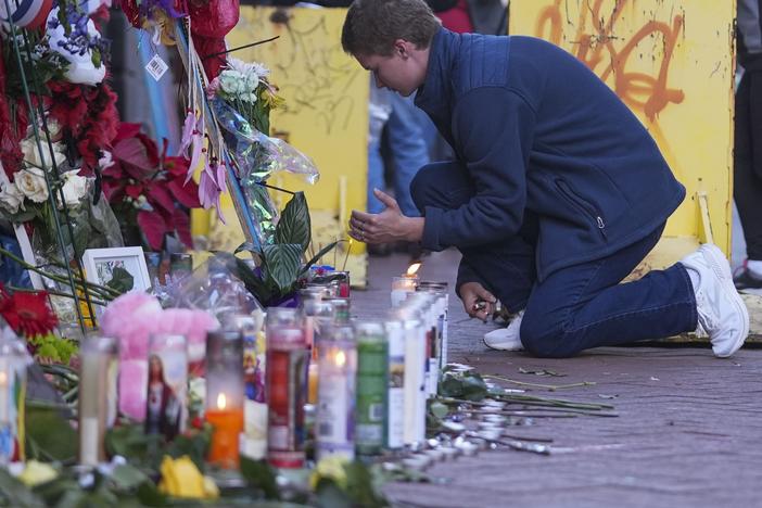 Nathan Williams, a University of New Orleans student, lights a candle at a memorial on Bourbon Street on Friday for the victims of a deadly truck attack on New Year's Day in New Orleans.
