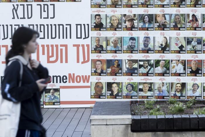 A woman in Kfar Saba, Israel, passes a wall on Monday covered with photos of hostages kidnapped to the Gaza Strip during the Oct. 7, 2023, Hamas-led attack.