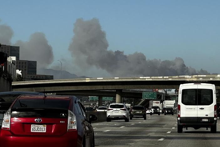 Smoke from a brush fire in the Pacific Palisades rises over the 405 freeway in Los Angeles on Tuesday.