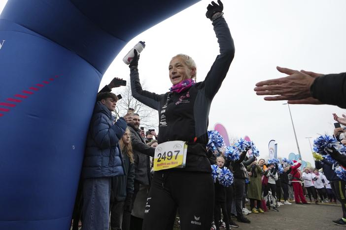 Belgian ultra runner Hilde Dosogne, center, is cheered on as she crosses the finish line during her 366th consecutive marathon in Ghent, Belgium, on Dec. 31, 2024.
