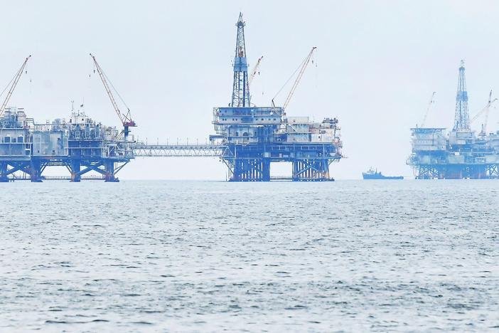 Three oil platforms are seen in federal waters off the southern California coast in 2021.  President Biden has prohibited new oil and gas leases in more than 625 million acres of federal ocean; existing leases are not affected.