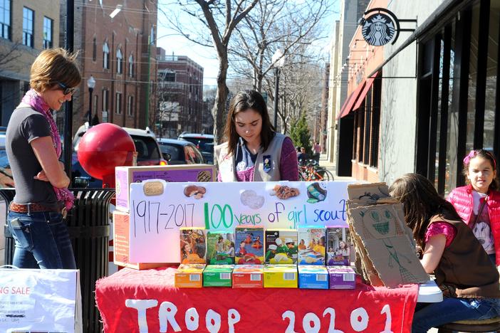 Trina Sheridan, left, watches as her her daughters Molly and Edie sell cookies in Chicago in 2017, the 100th year of Girl Scout cookies.