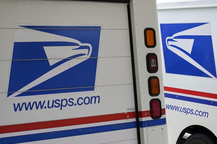 Mail delivery vehicles are parked outside a post office in Boys Town, Neb., in August 2020.