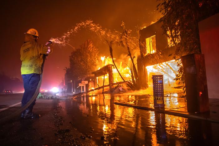A firefighter battles the Palisades Fire, which is burning homes on the Pacific Coast Highway amid a powerful windstorm in Los Angeles on Wednesday.