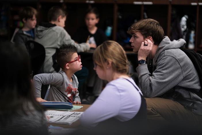 Kellen Hedler's classroom aid, Parker Van Buskirk, checks in with Kellen as he works on an assignment. Kellen is largely independent throughout the school day, but Van Buskirk is available in case he needs help.