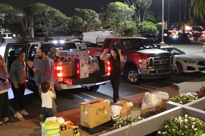 Lauren Gruel, pictured at right, celebrates having filled another truck bed with community-donated supplies on Thursday. She and her husband Andrew turned their Huntington Beach restaurant into a donation hub to support wildfire victims in Los Angeles.