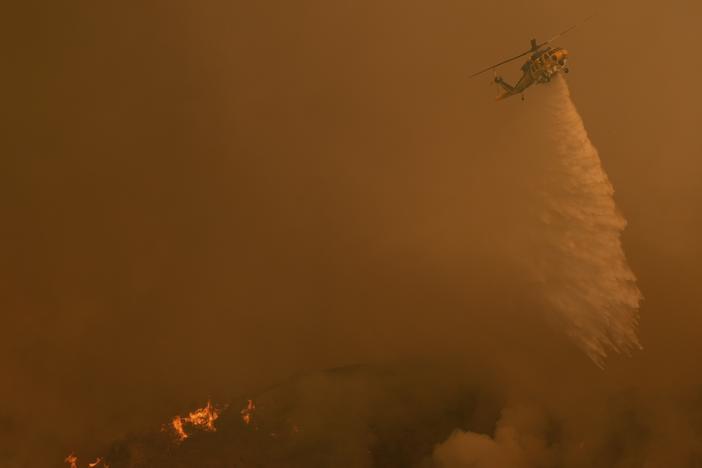 Water is dropped on the Palisades Fire by helicopter in Mandeville Canyon on Saturday in Los Angeles.
