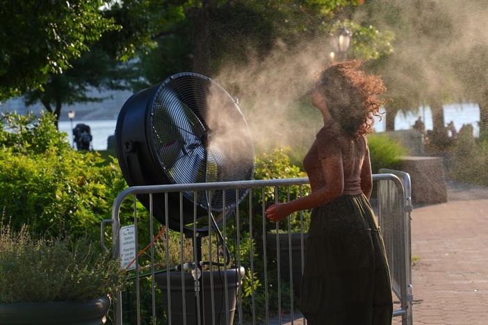 A woman cools off near a water-spraying fan during a New York City heat wave in July 2024. Heat broke records months in a row around the planet between 2023 and 2024.