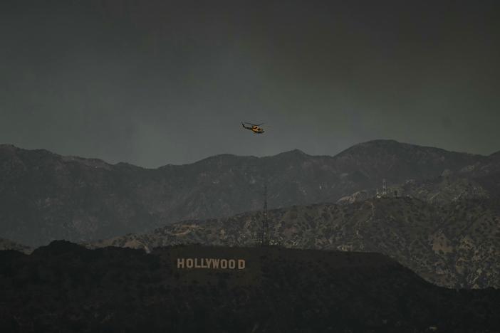 A firefighting helicopter flies above the Hollywood sign on Wednesday, Jan. 8.