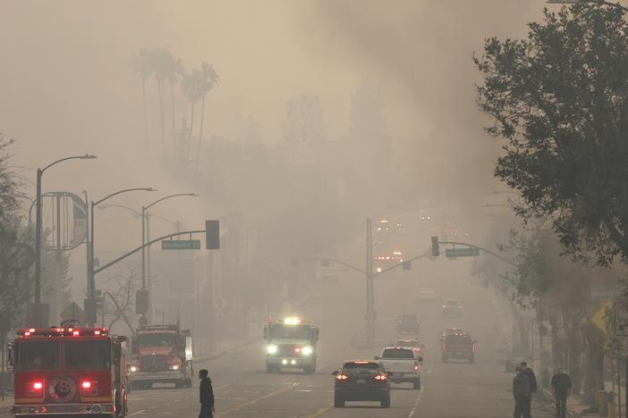 People walk through wildfire smoke in in Altadena, Calif., on Wednesday, as wildfires in Los Angeles County sharply worsened poor air quality.