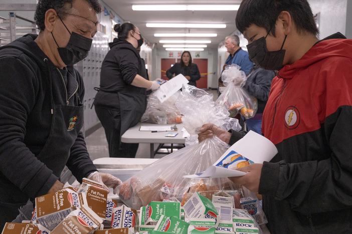 Jose Centeno hands food to LAUSD student Jesus Sanchez at Hollenbeck Middle School on Friday, Jan. 10.
