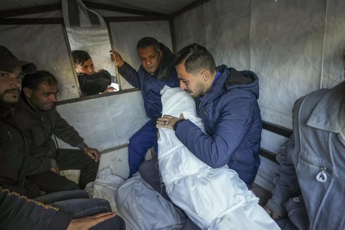Mohammad Eid carries the body of one of his three relatives killed on Saturday in an Israeli airstrike, as they are prepared for the funeral in Deir al-Balah, central Gaza Strip, Sunday, Jan. 12, 2025. (AP Photo/Abdel Kareem Hana)