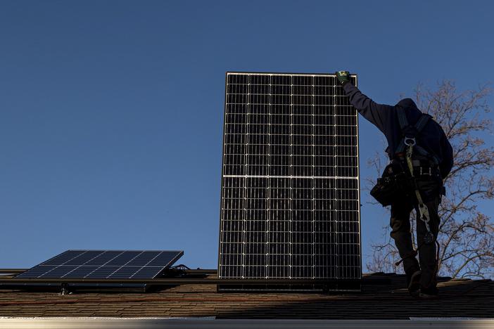 A contractor installs a solar panel on the roof of a home. Uncertainty over the future of a 30% federal tax credit has some homeowners rushing to get panels hooked to the grid before Trump becomes President.