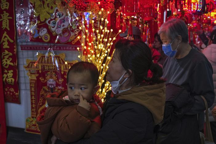 A woman carries a child as she shops at a New Year bazaar set up for the upcoming Chinese Lunar New Year, in Beijing on Jan. 13.