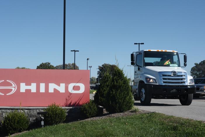 A truck passes a Hino sign in Williamstown, W.V., in 2017. The truck manufacturer, a Toyota subsidiary, has agreed to plea guilty to federal conspiracy charges and pay a total of $1.6 billion to settle civil claims after regulators discovered it was submitted fraudulent data to evade emissions standards.
