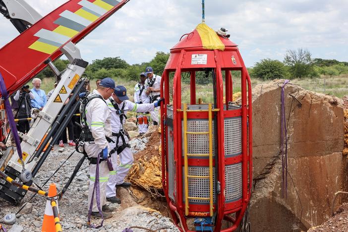Rescue workers look on as a cage is lifted from an abandoned gold shaft in Stilfontein on January 16, 2025.