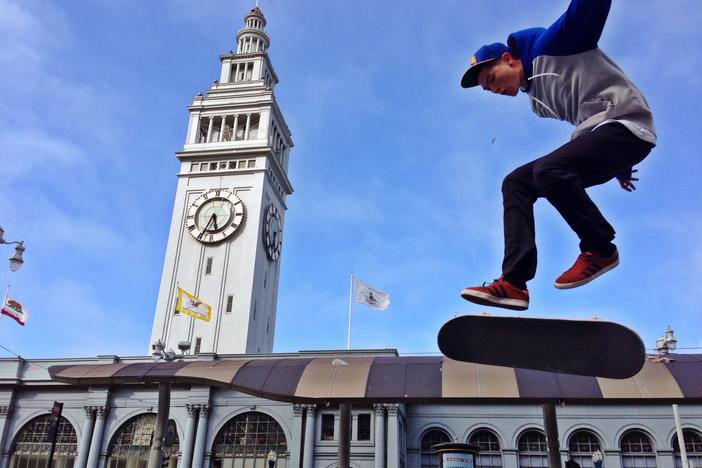 A young skateboarder riding in front of the Ferry Building on the Embarcadero in San Francisco California.