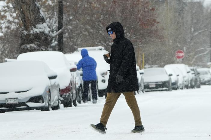 A pedestrian crosses First Avenue as a winter storm sweeps over the intermountain West, plunging temperatures into the single digits and bringing along a light snow in its wake Saturday, Jan. 18, 2025, in Denver.