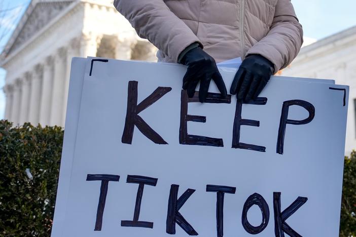 A content creator on TikTok holds a protest sign outside the Supreme Court building on Jan. 10 in Washington, D.C.