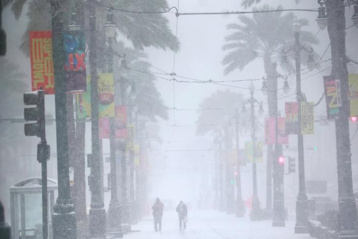 People make their way down a snowy Canal Street on Jan. 21 in New Orleans. A winter storm brought rare snowfall to the city.