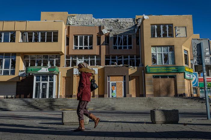 A woman walks in front of a war-ravaged shopping complex in Kherson, Ukraine, on Jan. 4. People in the city say cloudless days are most dangerous because Russian drones take advantage of the high visibility to swarm over the front-line city.