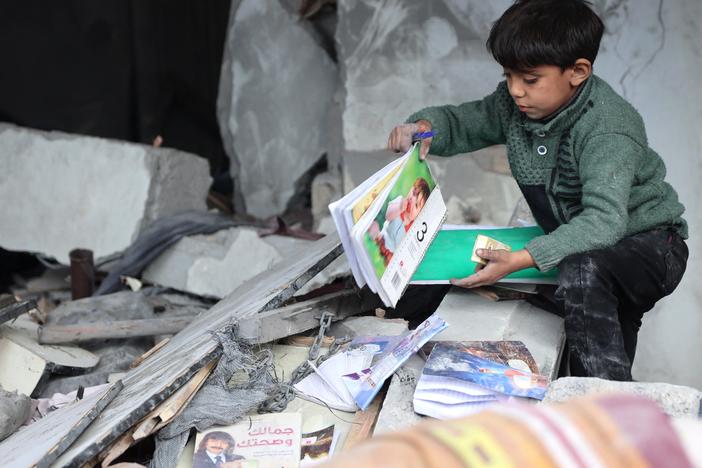 On Jan. 16, following a truce announcement amid the war between Israel and Hamas, a child recovers books from the rubble of a building hit in Israeli strikes the previous night in Jabalia, in the northern Gaza Strip.