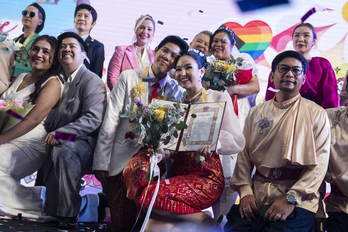 Same-sex couples pose for pictures at a marriage registration event at Paragon shopping mall in Bangkok, on Thursday.