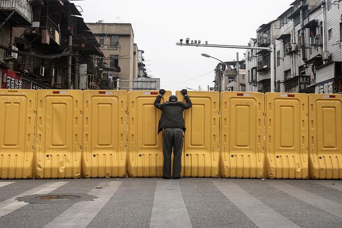 One man talks to another man on March 8, 2020, through a makeshift barricade wall built to control entry and exit to a residential compound in Wuhan, Hubei, China.