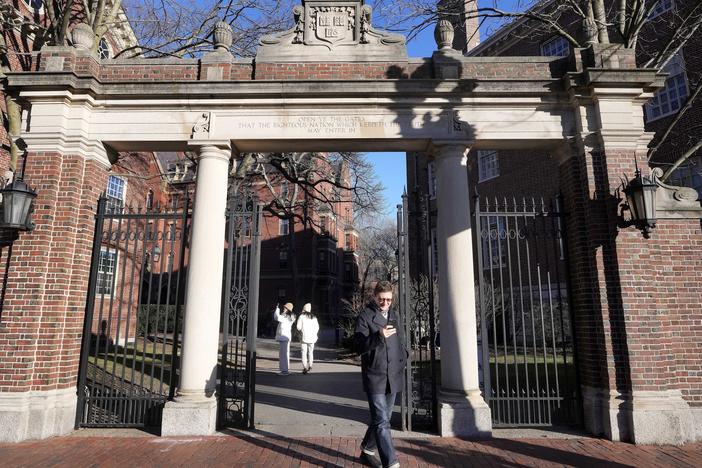 A passerby walks through a gate to the Harvard University campus, Tuesday, Jan. 2, 2024, in Cambridge, Mass.
