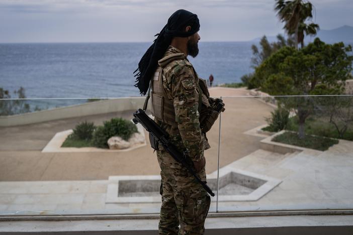 A fighter with Hayat Tahrir al-Sham, the group that led the overthrow of the Assad regime, stands on the terrace of former Syrian President Bashar al-Assad's family villa outside Latakia. After the Assad regime fell last month, the family's properties were left abandoned. One of those was the Assad summer home, with a private beach on the Mediterranean.