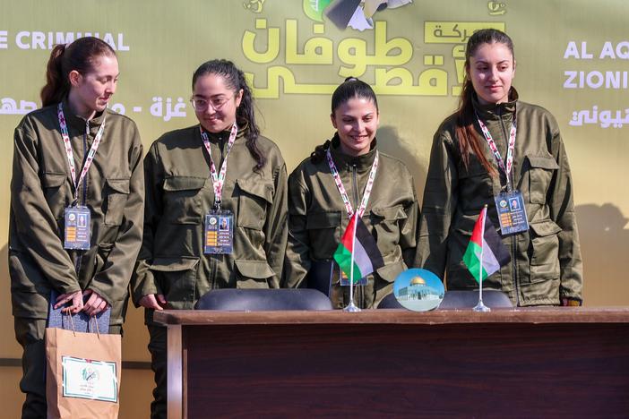 Four Israeli hostages stand on a stage before Hamas fighters hand them over to a team from the Red Cross in Gaza City on Saturday.