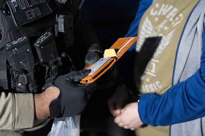 U.S. Immigration and Customs Enforcement officers look at the identification of a person detained on Monday.